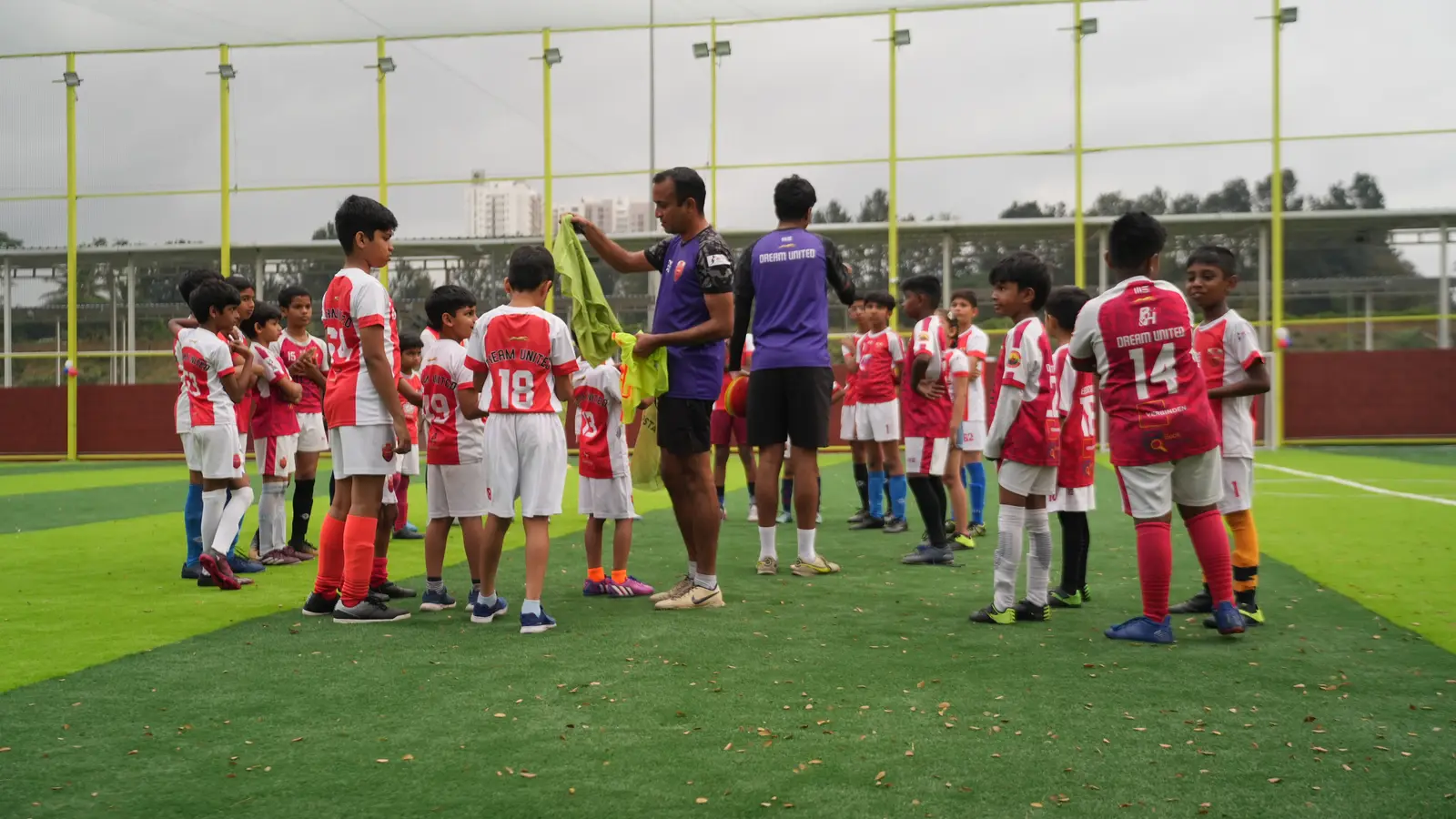 Football coaches handing out training bibs to young players at Coliseo Nice Road