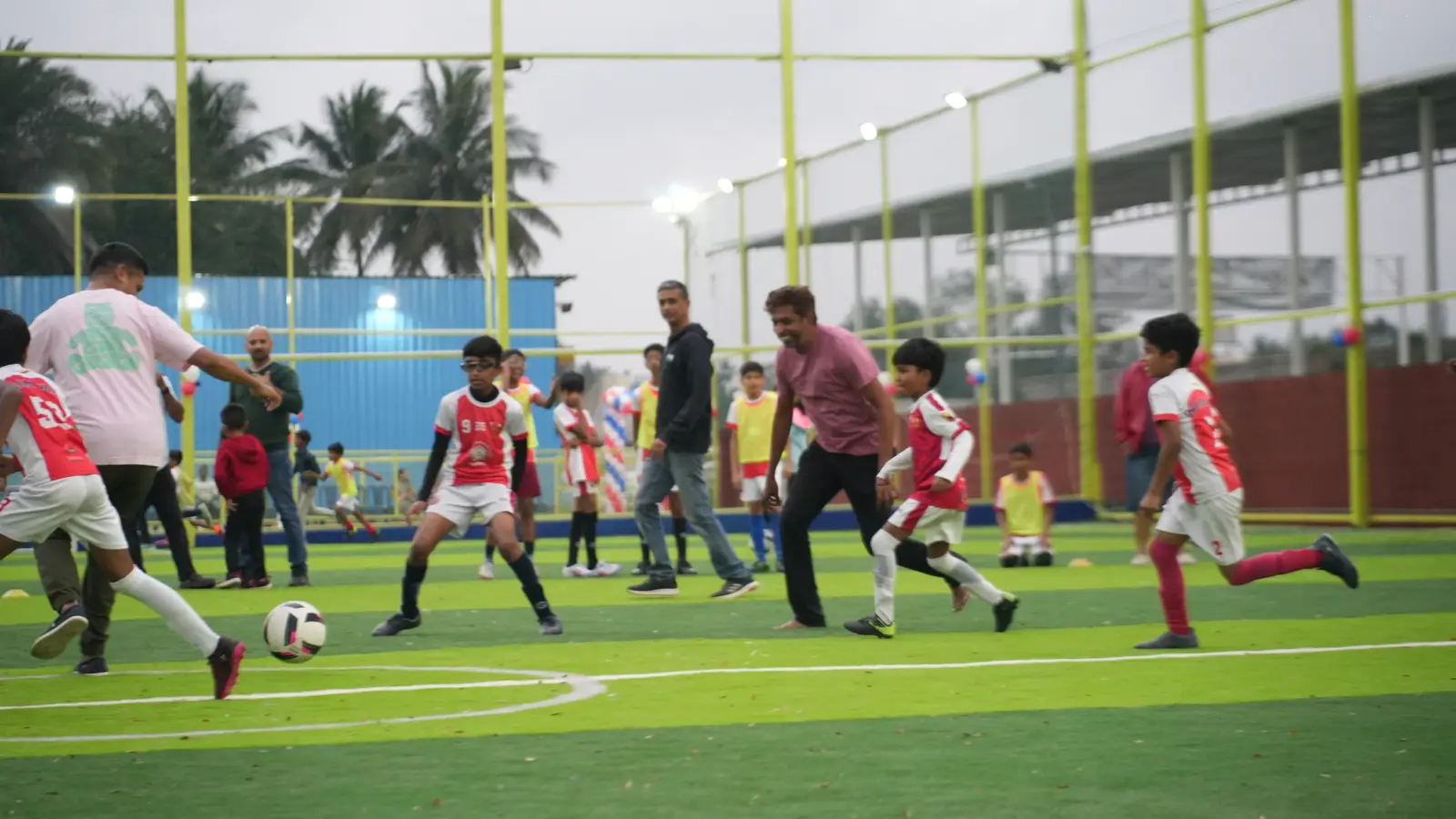 Adults and kids playing a friendly football game together at Coliseo Nice Road