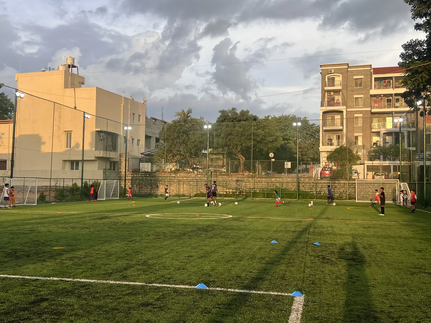 Golden-hour football training on the turf at Coliseo Noble Residency