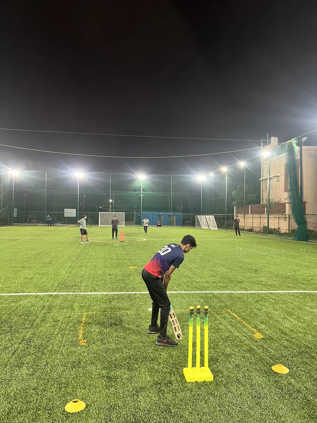Batsman at the stumps under floodlights at Coliseo Noble Residency